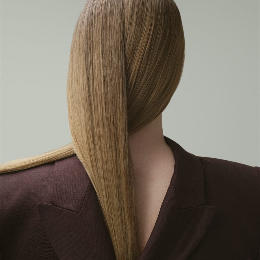 Back view of glossed blonde hair falling over a dark blazer